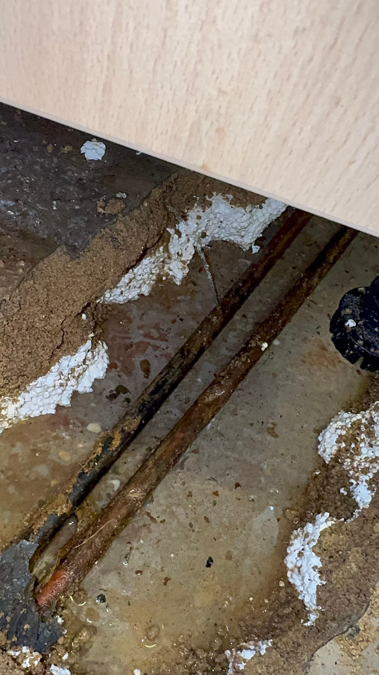 Exact leak location on corroded copper pipe beneath kitchen floor 